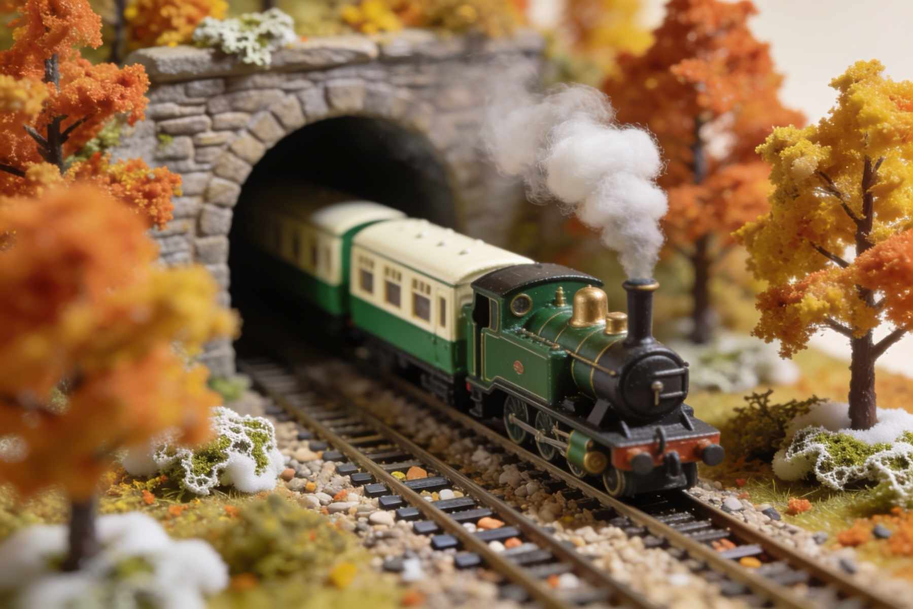 A green narrow-gauge engine pulling cream and green coaches out of a stone tunnel among autumn trees