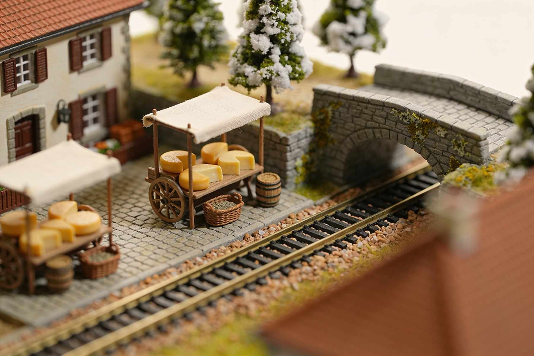 Market stalls with wheels of cheese and baskets beside the railway, a stone bridge over the track